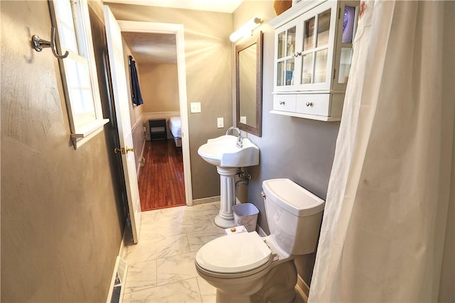 bathroom with marble finish floor, baseboards, and toilet