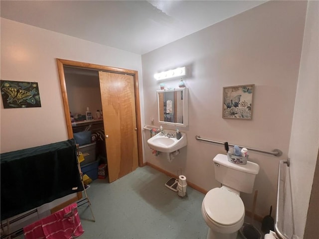 bathroom with toilet, concrete flooring, and sink