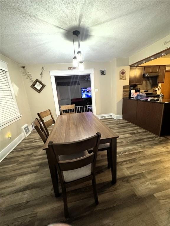 dining space with dark hardwood / wood-style floors and a textured ceiling