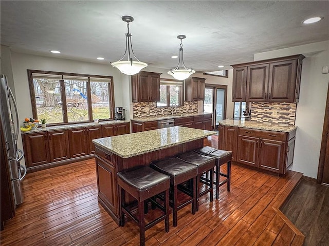 kitchen with light stone countertops, a center island, pendant lighting, and a breakfast bar