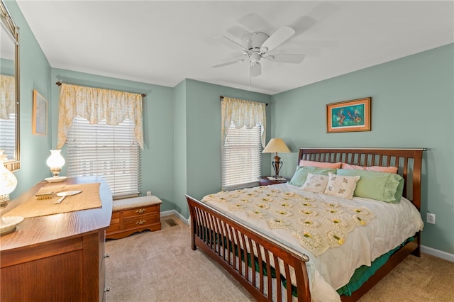 bedroom with ceiling fan, multiple windows, and light carpet