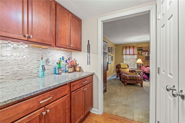 kitchen featuring light colored carpet, light stone countertops, and decorative backsplash