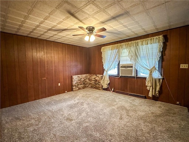 spare room with wood walls, carpet floors, cooling unit, a baseboard heating unit, and ceiling fan