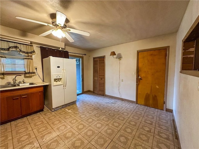 kitchen featuring sink, white fridge with ice dispenser, and ceiling fan