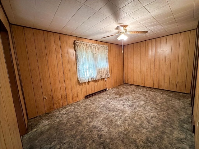 carpeted spare room featuring ceiling fan and wood walls