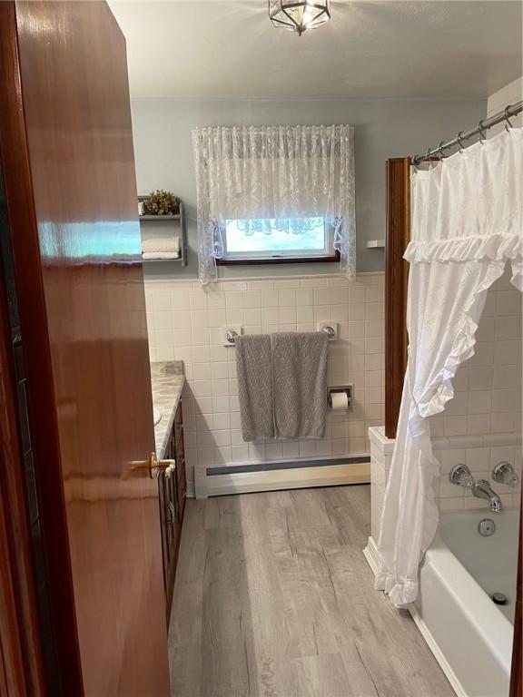 bathroom with baseboard heating, wood-type flooring, tile walls, and vanity