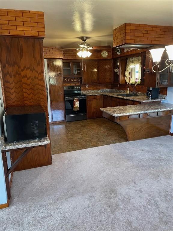 kitchen with ceiling fan, kitchen peninsula, sink, and black appliances