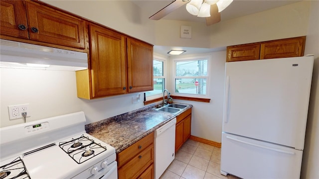 kitchen featuring sink, white appliances, light tile patterned floors, ceiling fan, and dark stone counters