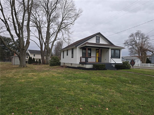 view of front of house with a porch, a front yard, and a shed