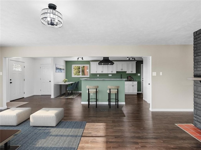 living room featuring dark wood-type flooring, a large fireplace, and an inviting chandelier