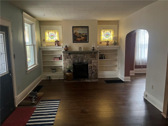 unfurnished living room with a stone fireplace and dark hardwood / wood-style floors