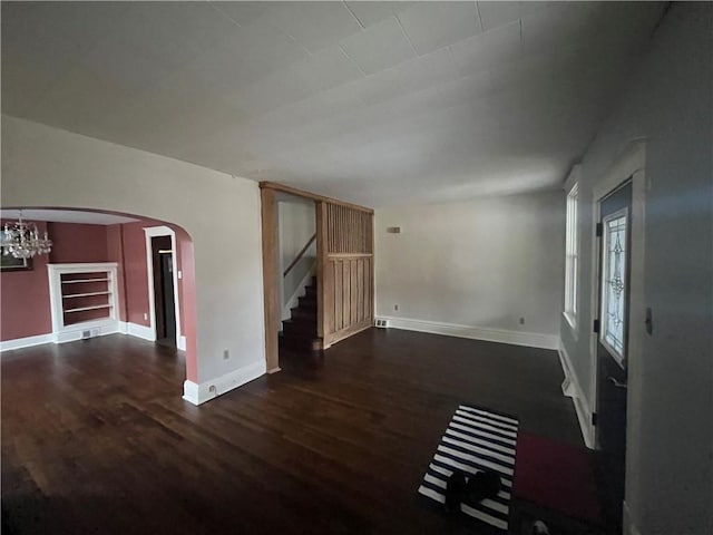 unfurnished living room featuring an inviting chandelier and dark hardwood / wood-style floors