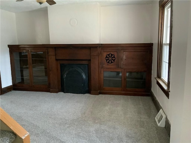 unfurnished living room featuring plenty of natural light, ceiling fan, and carpet flooring