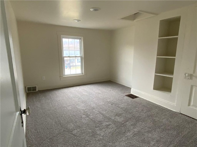 unfurnished room with built in shelves and carpet flooring