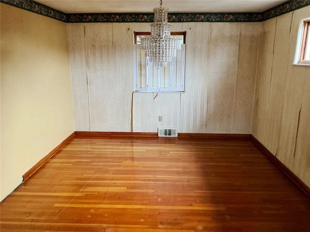 empty room featuring hardwood / wood-style flooring and an inviting chandelier