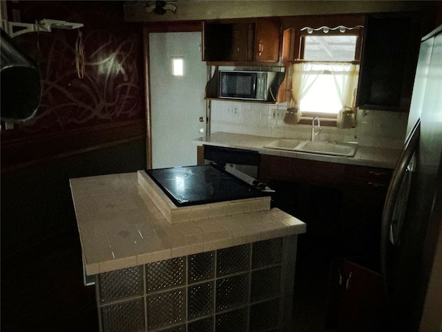 kitchen with sink, tile countertops, and refrigerator