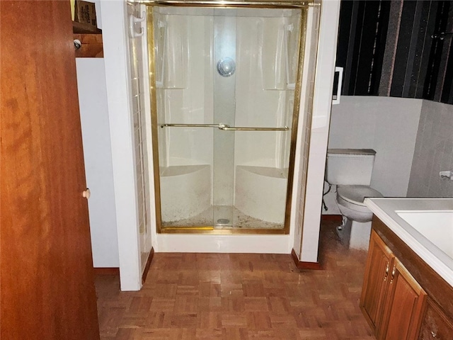 bathroom with parquet flooring, vanity, toilet, and a shower with door