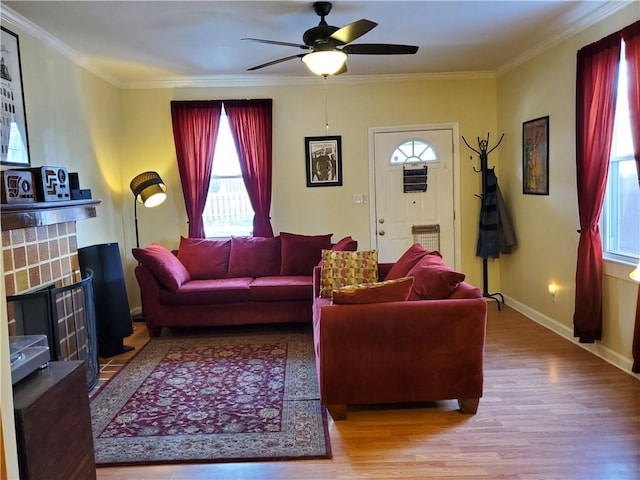 living room featuring crown molding, wood-type flooring, a tile fireplace, and ceiling fan