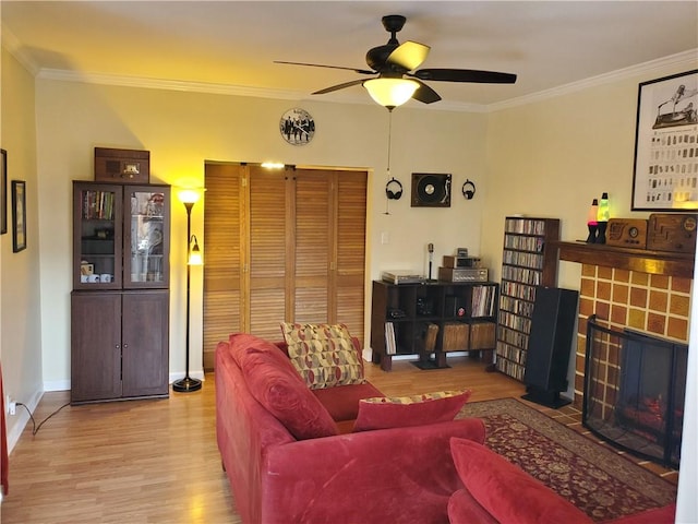 living room featuring light hardwood / wood-style flooring, ornamental molding, a tile fireplace, and ceiling fan