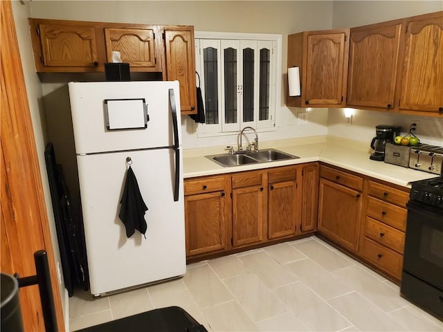 kitchen with white refrigerator, black range oven, sink, and light tile patterned floors