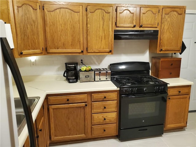 kitchen featuring tasteful backsplash, stainless steel refrigerator, light tile patterned flooring, and black gas range oven