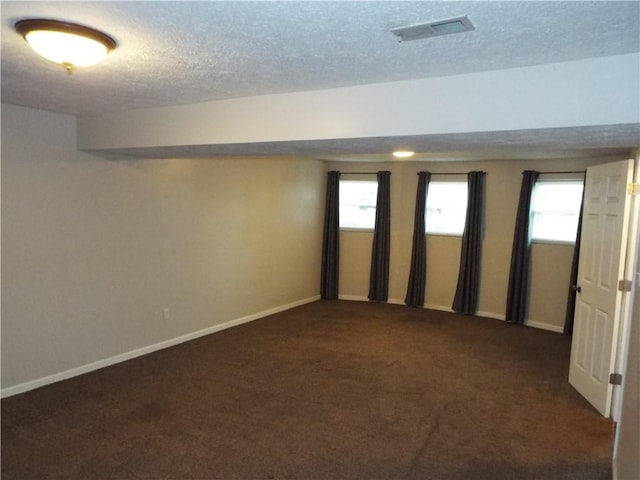 spare room featuring a textured ceiling and dark colored carpet