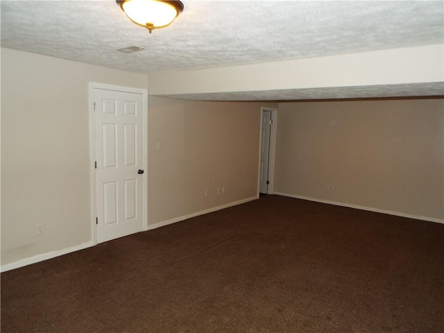 basement featuring dark carpet and a textured ceiling