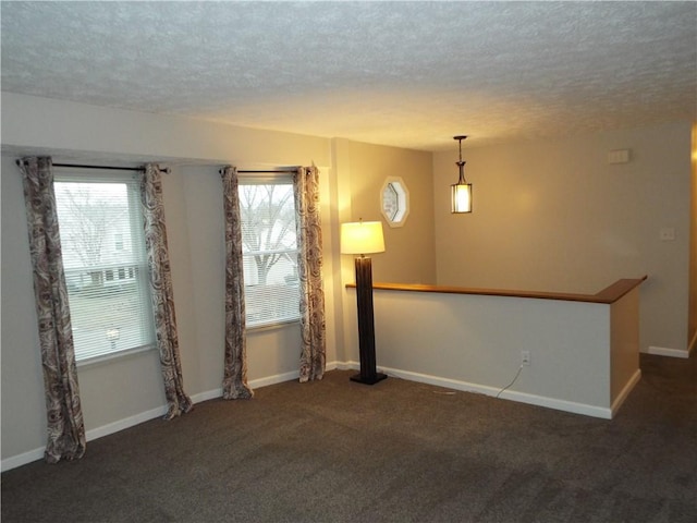 empty room featuring a textured ceiling and dark carpet