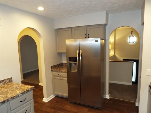 kitchen with pendant lighting, dark wood-type flooring, gray cabinets, stone countertops, and stainless steel fridge with ice dispenser