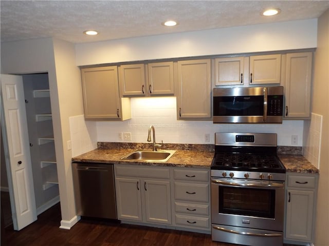 kitchen featuring sink, dark wood-type flooring, gray cabinets, backsplash, and stainless steel appliances