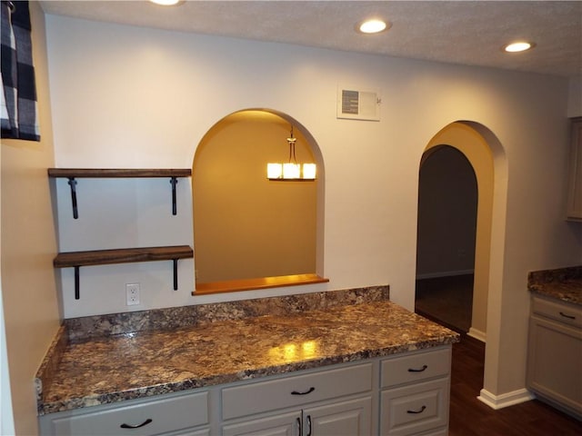 kitchen featuring pendant lighting, gray cabinetry, dark hardwood / wood-style flooring, and dark stone countertops