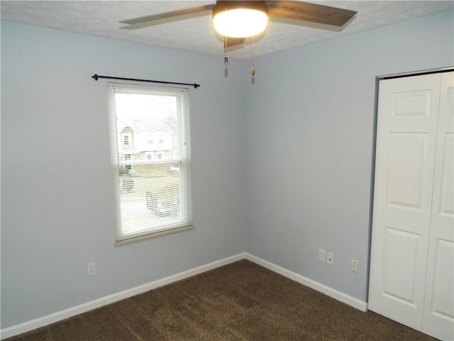 spare room featuring dark carpet and ceiling fan