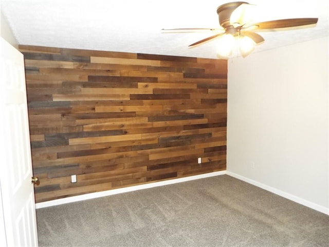 carpeted empty room featuring ceiling fan and wood walls