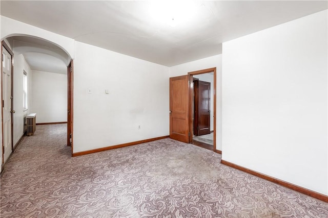 unfurnished room featuring radiator heating unit and light colored carpet