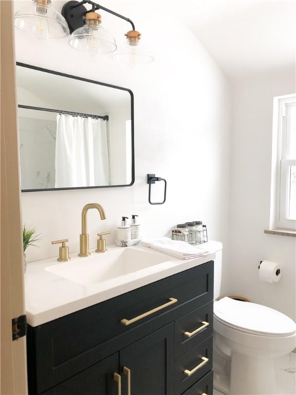 bathroom featuring vanity, curtained shower, and toilet