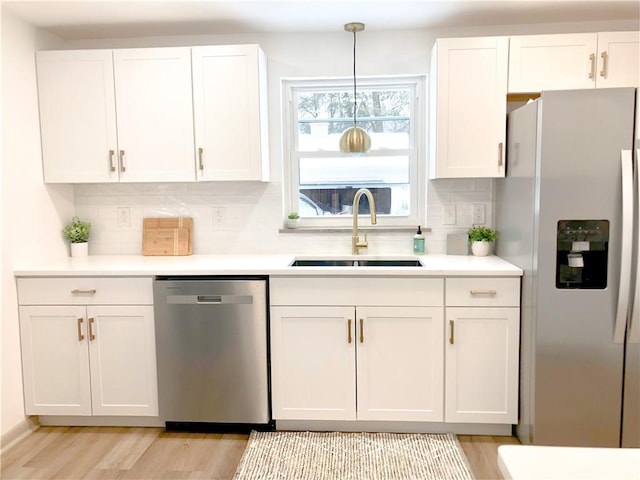 kitchen with sink, white cabinetry, tasteful backsplash, pendant lighting, and stainless steel appliances