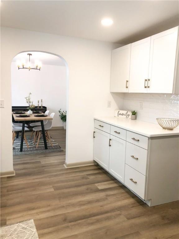 kitchen featuring white cabinetry, backsplash, decorative light fixtures, and dark wood-type flooring