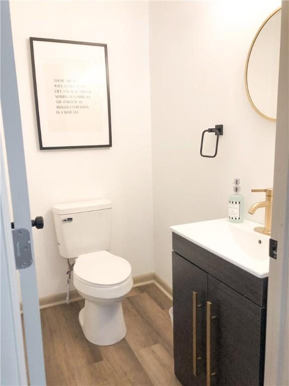 bathroom with hardwood / wood-style flooring, vanity, and toilet