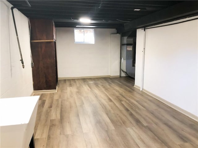 basement featuring heating unit and light hardwood / wood-style flooring