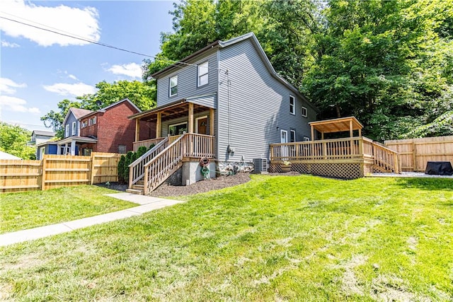 back of property with central AC, a deck, and a lawn