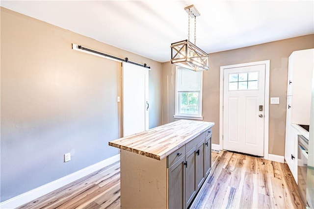 kitchen with gray cabinetry, decorative light fixtures, light wood-type flooring, and a kitchen island