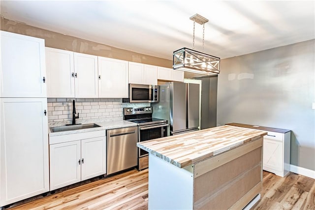 kitchen featuring a kitchen island, white cabinetry, sink, hanging light fixtures, and stainless steel appliances