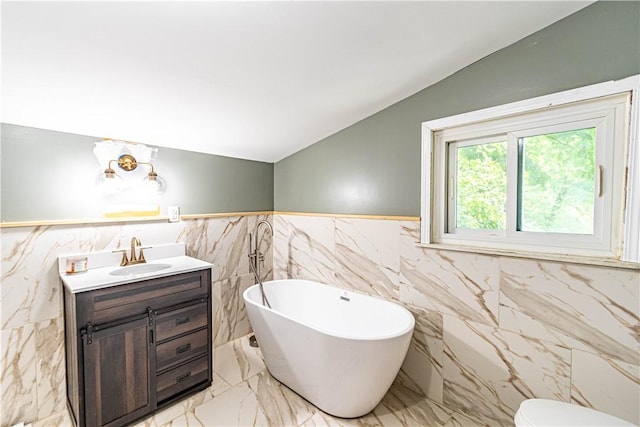 bathroom featuring vaulted ceiling, vanity, and a tub to relax in