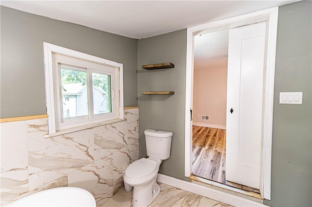 bathroom with tile walls and toilet