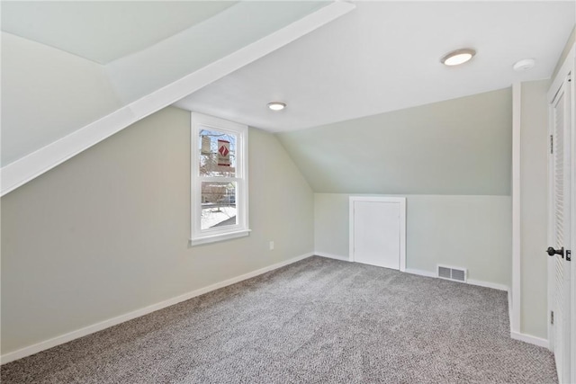 additional living space featuring vaulted ceiling and carpet flooring