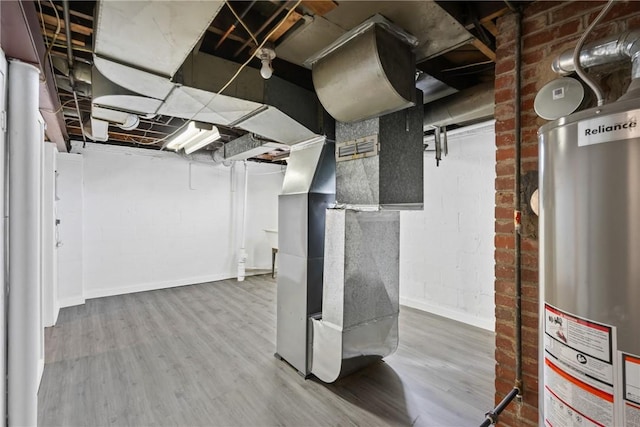 basement featuring hardwood / wood-style flooring, gas water heater, brick wall, and heating unit