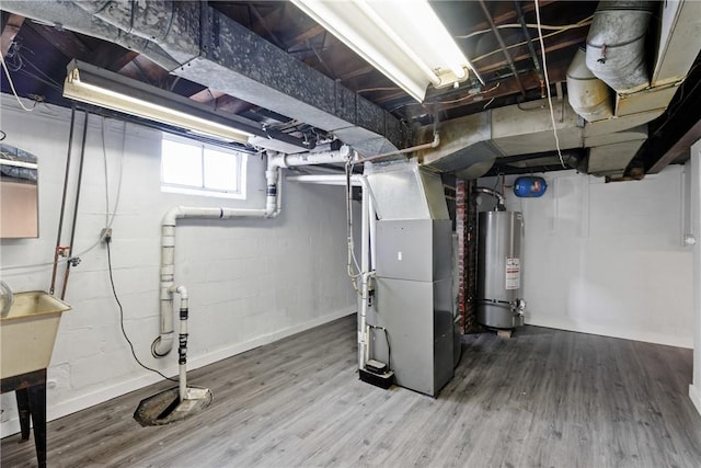 basement featuring heating unit, hardwood / wood-style floors, and gas water heater