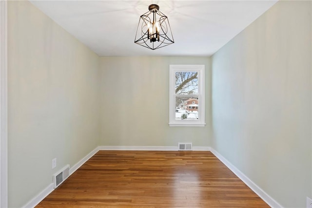 unfurnished dining area with an inviting chandelier and wood-type flooring