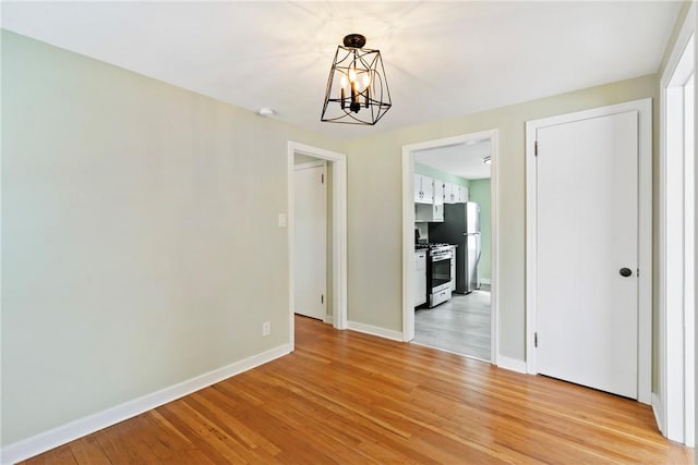 unfurnished dining area featuring light hardwood / wood-style floors and a notable chandelier