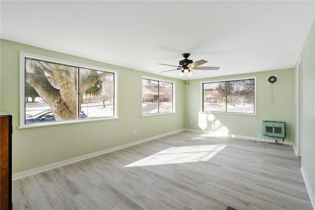 spare room featuring heating unit, plenty of natural light, light hardwood / wood-style floors, and ceiling fan